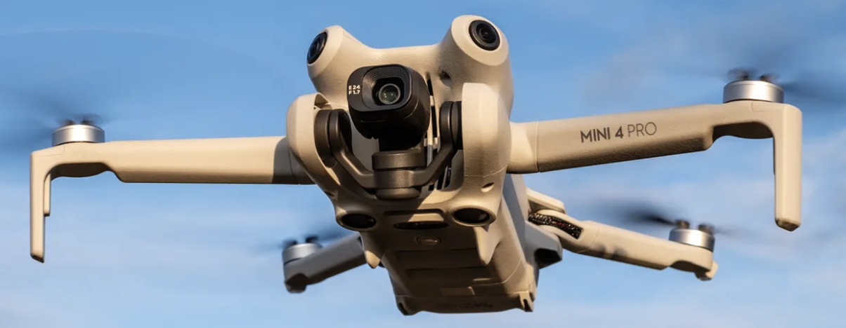 DJI Mini 4 Pro drone in flight against a blue sky